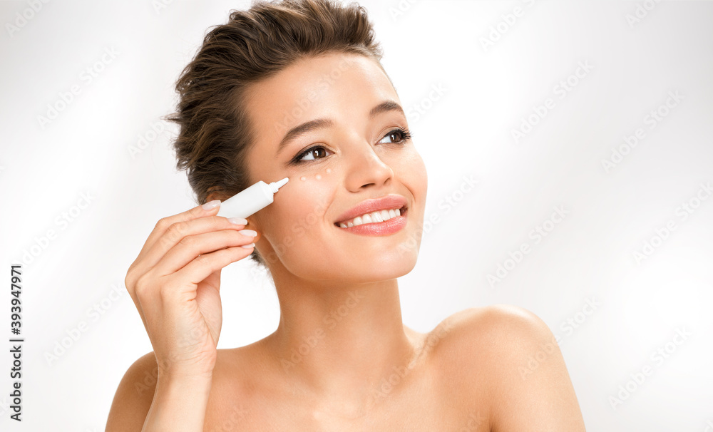 Beautiful woman using cream around the eyes. Photo of woman with perfect skin on white background. Beauty and skin care concept Beautiful woman using cream around the eyes. Photo of woman with perfect skin on white background. Beauty and skin care concept
