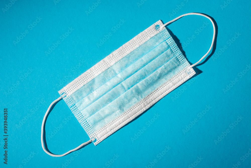 Disposable medical mask on a blue background.
