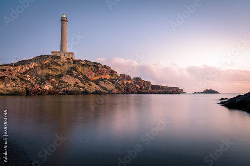 Lighthouse of Cabo de Palos reflected in the water of the beach at sunrise, Murcia, Spain