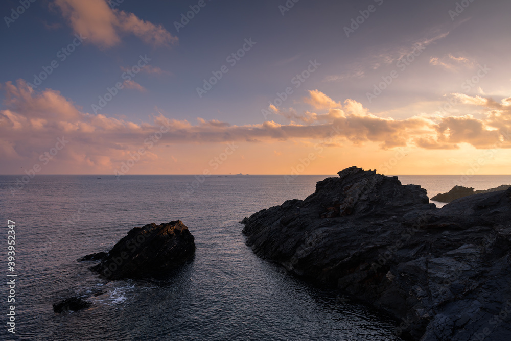 Fototapeta premium Beautiful cloudy sunrise from a cliff in Cabo de Palos with the sun reflected in the sea water, Murcia, Spain