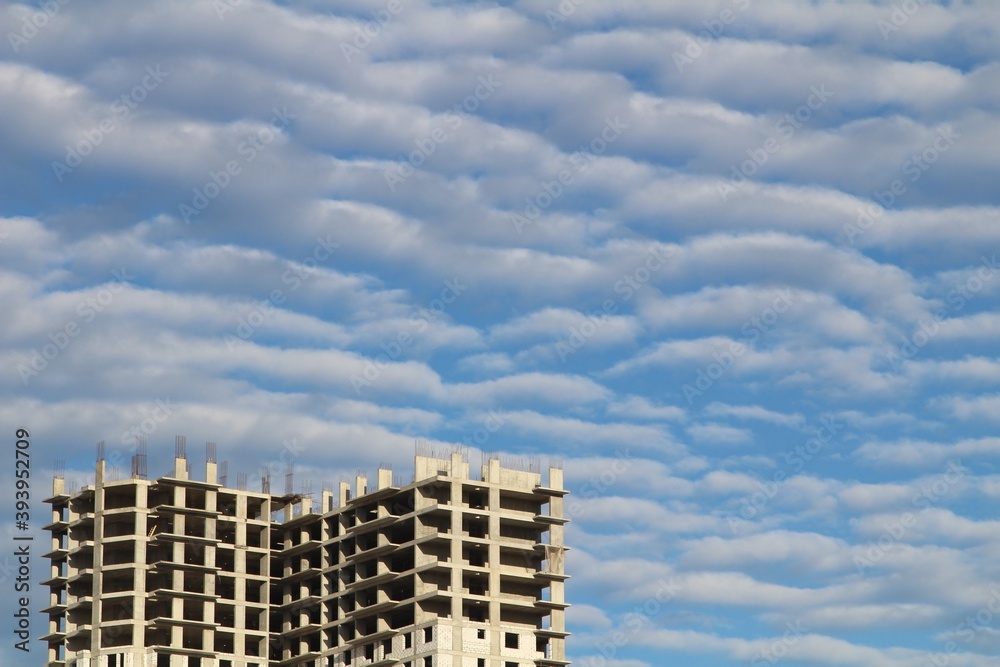 A residential building under construction against a beautiful cloudy sky A residential building under construction against a beautiful cloudy sky