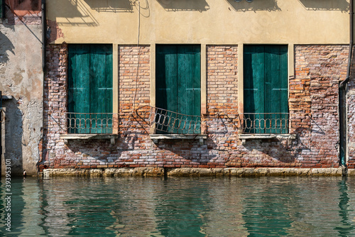 Wohnhaus mit drei französischen Fenstern mit grünen Fensterläden an einem Kanal in Castello, Venedig  © Anita Pravits