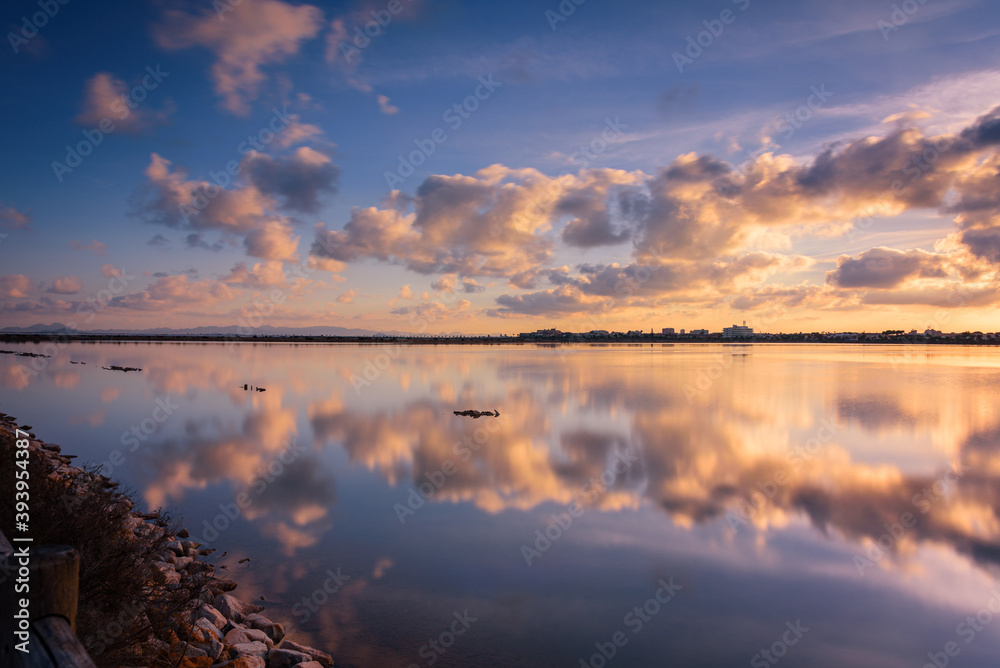 Reflection on the water of a salt lake of a beautiful sunset with a sky full of clouds in Regional Park of the Salinas and Arenales de San Pedro del Pinatar, Murcia, Spain Reflection on the water of a salt lake of a beautiful sunset with a sky full of clouds in Regional Park of the Salinas and Arenales de San Pedro del Pinatar, Murcia, Spain