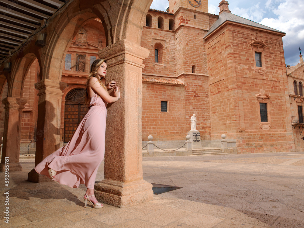 Pretty young woman on a column in long pink dress