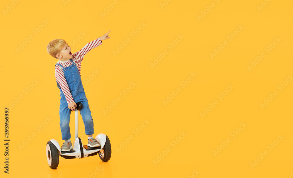 Funny child boy boy riding on hoverboard or gyroscooter on yellow background. Advertising Electrical transport for children Funny child boy boy riding on hoverboard or gyroscooter on yellow background. Advertising Electrical transport for children