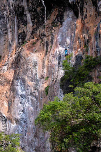 A male rock climber scales the famous limestone cliff face on Railay beach