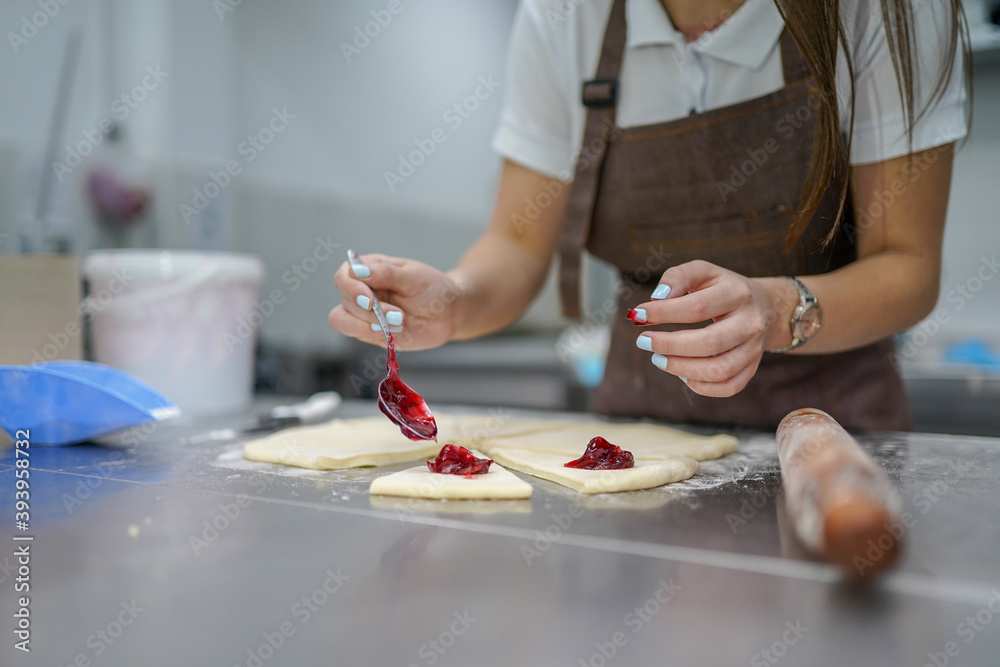 Young woman making croissants in bakery kitchen