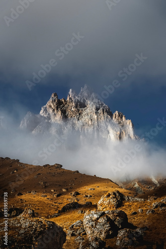 Mountain peaks in the clouds against the backdrop of a beautiful sunset. Travel and hiking concept