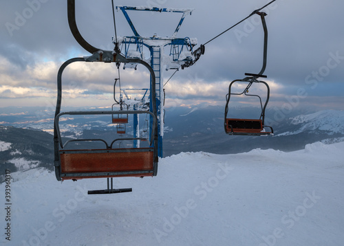 Alpine resortr ski lift with seats going over the sunset mountain skiing  slopes in extremally windy weather photo