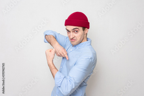 Smug guy in a red cap and blue shows his muscles at the camera, portrait