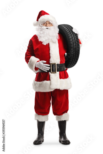 Full length portrait of santa claus carrying a car tire on his shoulder