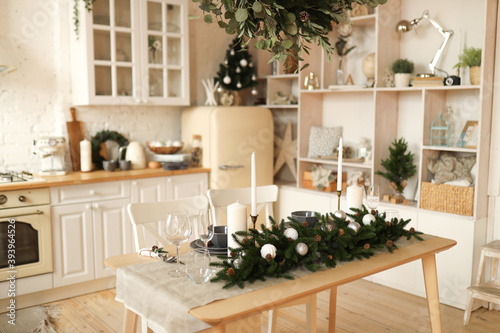 Interior of a light kitchen decorated with Christmas decorations and fir plants in natural materials and colors in a cozy home