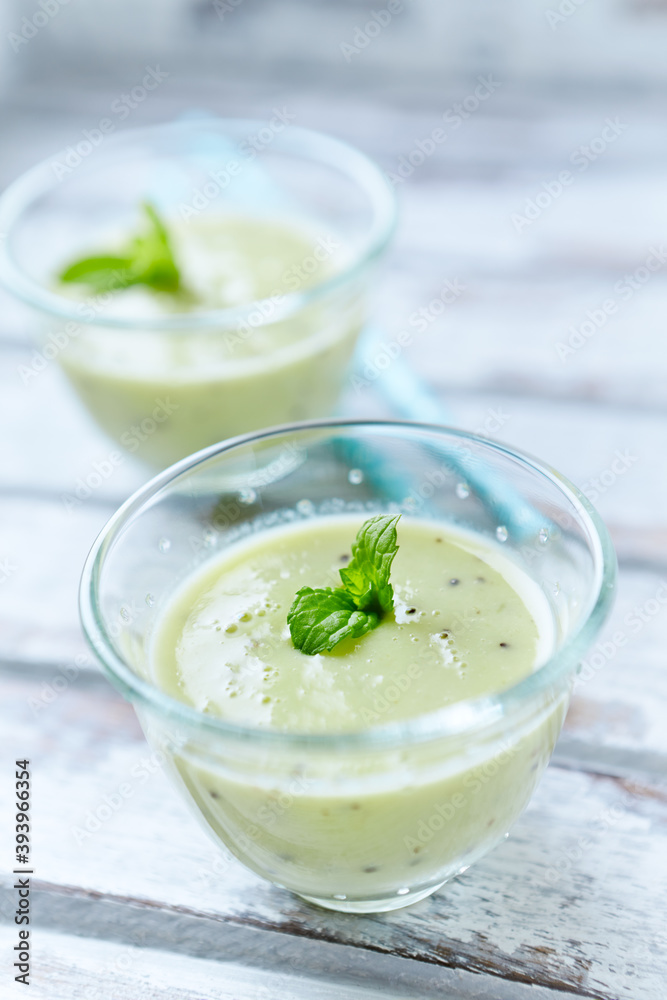 Green smoothie topped with chia seeds on bright wooden background. Close up. Green smoothie topped with chia seeds on bright wooden background. Close up.