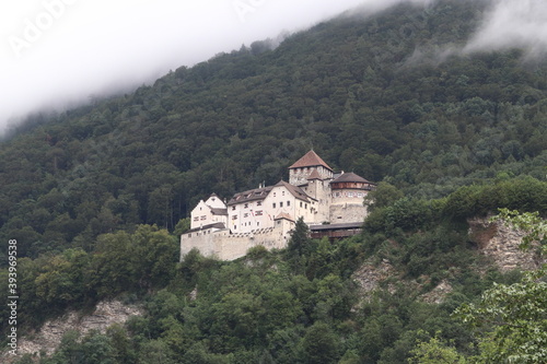 Vaduz / Liechtenstein - August 10 2019: Castle of Vaduz high in the mountain on top of town Vaduz, trees covered in clouds