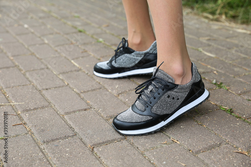 female feet wearing black sneakers outdoors © Петр Смагин