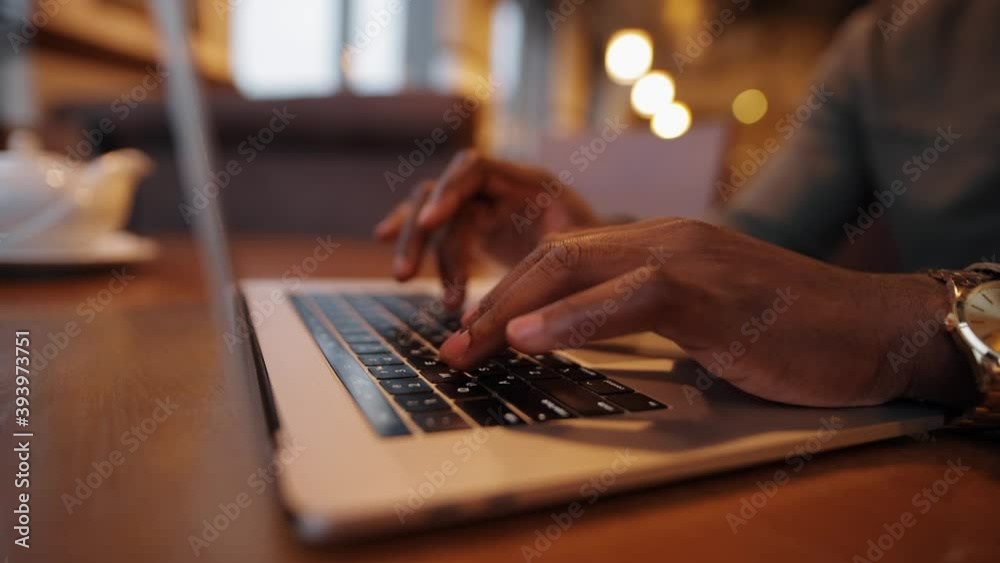 African-American male fingers working by laptop keyboard in a cafe African-American male fingers working by laptop keyboard in a cafe