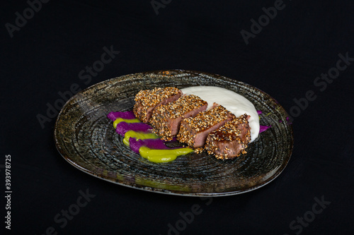 Tuna steak on black plate with decoration