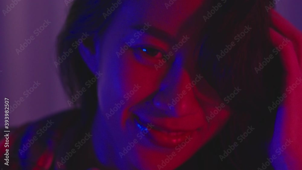 Young Asia lady drinking beer having fun and dancing happy moment New Year neon night party event celebration in living room at home. Social distancing, quarantine for coronavirus. Close up shot. Young Asia lady drinking beer having fun and dancing happy moment New Year neon night party event celebration in living room at home. Social distancing, quarantine for coronavirus. Close up shot.