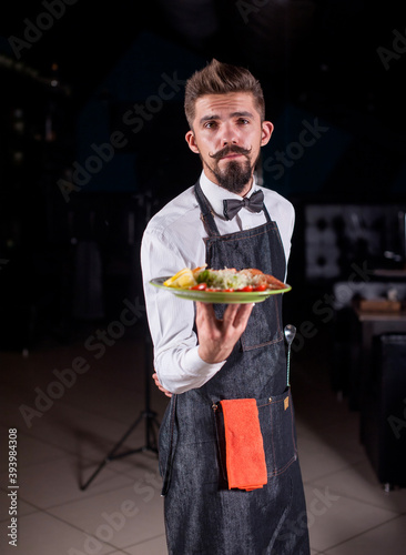 Whiskered restaurant employee carries appetizing dish in the restaurant. photo