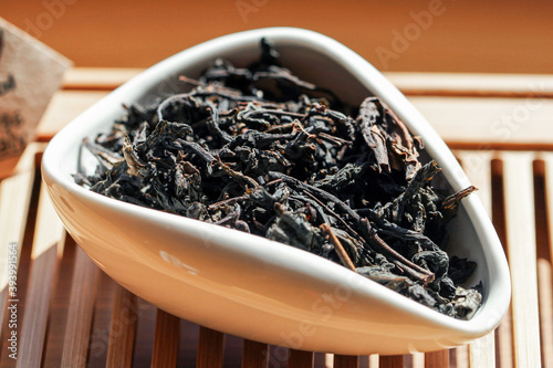 Chinese green tea Phoenix Mountain Oolong (Fenghuang dan cong) in Tea presentation vessel, macro picture with blurred background.