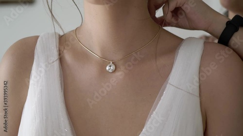 Bridesmaid helping to wear necklace for bride. Wedding morning dressing