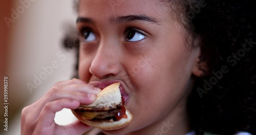 Little girl eating burger. Child taking a bite of hamburger