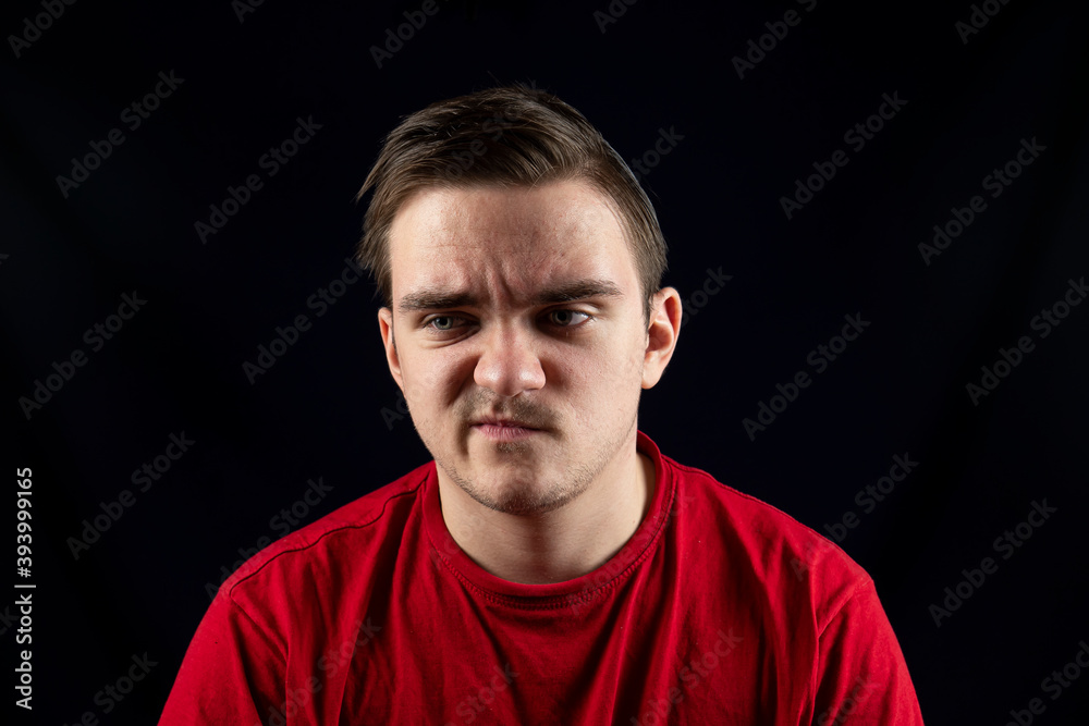 Young man in casual t-shirt standing against isolated dark background