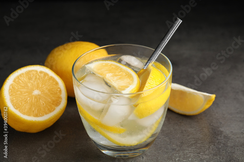 Soda water with lemon slices and ice cubes on grey table