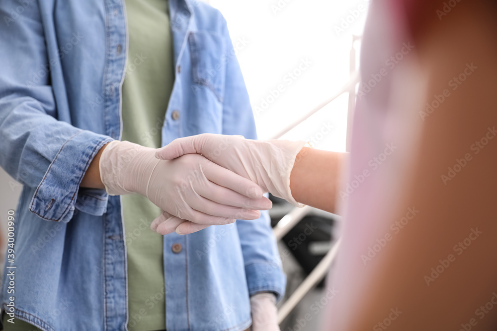 People in white medical gloves shaking hands on blurred background, closeup People in white medical gloves shaking hands on blurred background, closeup