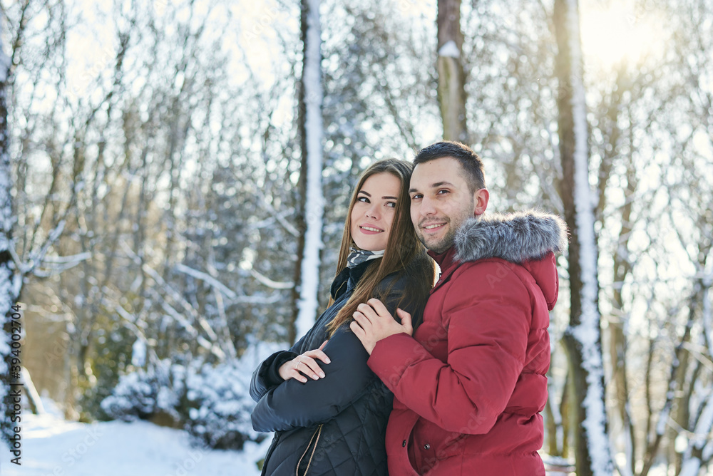 Young couple in love, enjoying winter weather outside in park forest. Brunette man in red jacket hugging woman in black. Christmas and new year holidays joy. Romantic date, relationship. Young couple in love, enjoying winter weather outside in park forest. Brunette man in red jacket hugging woman in black. Christmas and new year holidays joy. Romantic date, relationship.