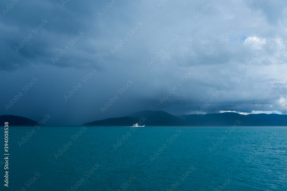 small white boat sailing in a tropical storm