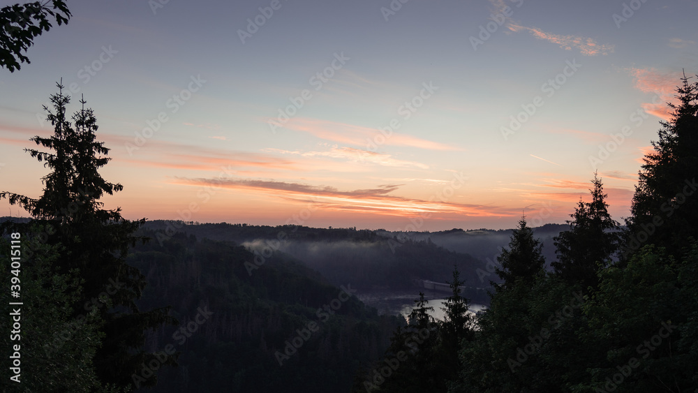 See im Tal, umgeben von einem Tannenwald bei Sonnenaufgang