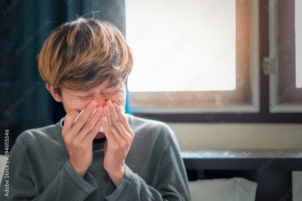 Sick asian man have hight fever flu and sneezing into tissue on bed in bedroom, Medical and health concept, Selective focus. Sick asian man have hight fever flu and sneezing into tissue on bed in bedroom, Medical and health concept, Selective focus.