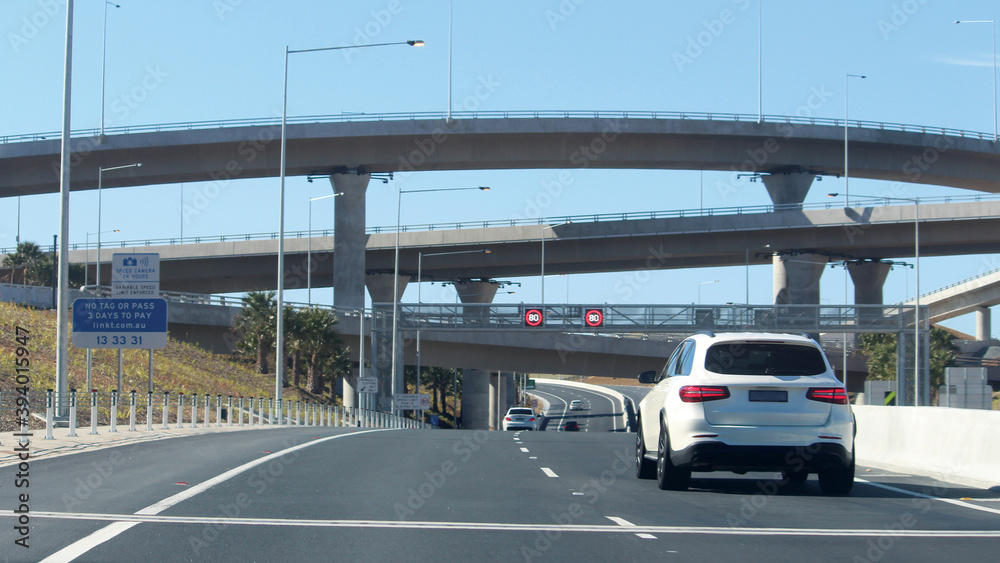 New westconnex motorway and over passes. A white car travelling on the road. 80km speed limit signs. Sydney, Australia New westconnex motorway and over passes. A white car travelling on the road. 80km speed limit signs. Sydney, Australia