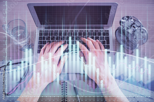Multi exposure of man s hands typing over computer keyboard and forex graph hologram drawing. Top view. Financial markets concept.