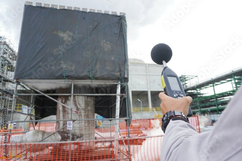 Hand of Environmental officer holding to use sound level meter for monitor is part of the prevention of environmental impacts at Chemical plant area or refinery factory.