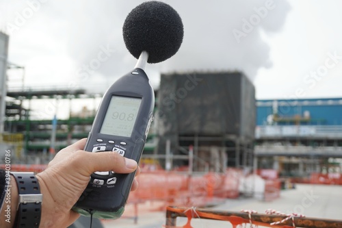 Hand of Environmental officer holding to use sound level meter for monitor is part of the prevention of environmental impacts at Chemical plant area or refinery factory. photo
