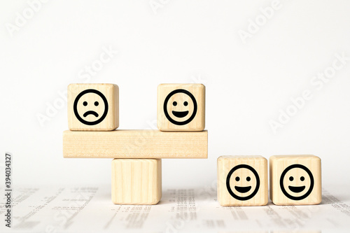 Close up custome choose smiley face and blurred sad face icon on wood cube, Service rating, satisfaction concept.