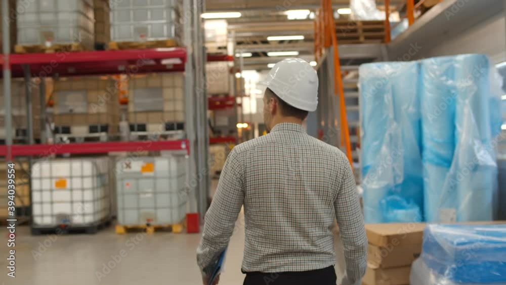 Back view of manager and supervisor in hardhat discussing inventory in factory warehouse. Back view of manager and supervisor in hardhat discussing inventory in factory warehouse.