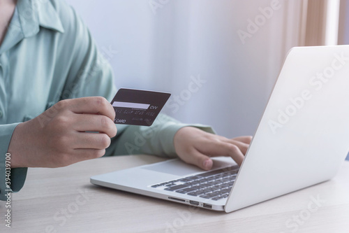 Asian business women are keying in their credit card details to pay online. She is in the office.