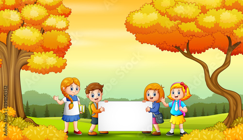 Autumn park landscape with school kids holding blank sign