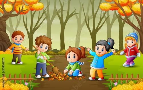 Happy volunteers kids cleaning up autumn leaves in the park