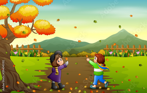 Happy girls catching falling leaf in autumn landscape