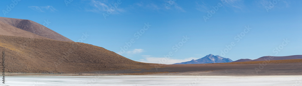 Panorama of mountains and white salt pan in Eduardo Avaroa Andean Fauna National Reserve against a clear blue sky, Bolivia
