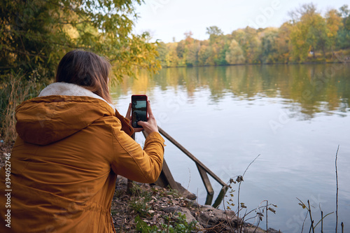 Beautiful woman taking pictures of the lake on a smartphone