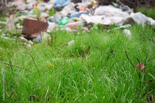 Green lawn in the forest littered with garbage polluting
