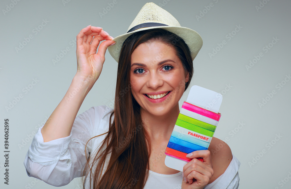 Smiling woman traveler touching hat with raised hand holding passport with ticket Smiling woman traveler touching hat with raised hand holding passport with ticket