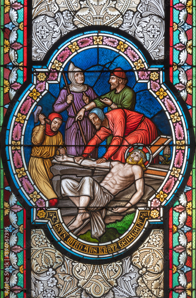 VIENNA, AUSTIRA - OCTOBER 22, 2020: The  Jesus is nailed to the crosss scene on the stained glass in  in church Pfarrkirche Kaisermühlen by workroom Tiroler Glasmalerei-Anstalt from end of 19. cent..
