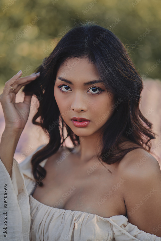 Lifestyle fashion portrait of stylish young asian woman wearing beige outfit posing at the flowers field