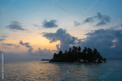 Sunset, ocean and coconut trees near paradisiac island